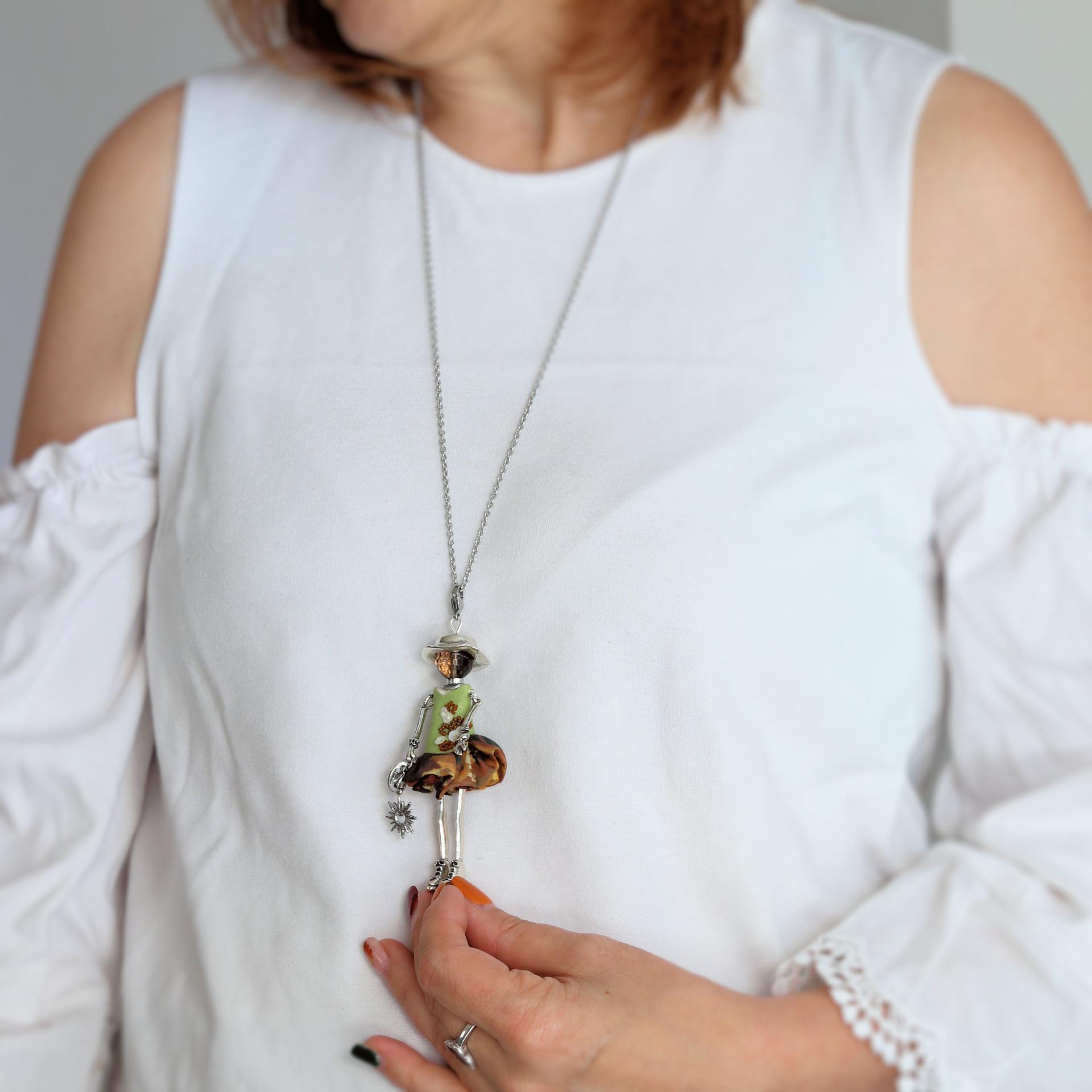 Collier vert femme porté sur un pull : une poupée talisman légère de 29 g, pour vous accompagner tous les jours.