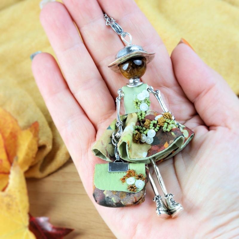 Collier œil de tigre femme, poupée en robe d'automne brodée main, posée dans une main