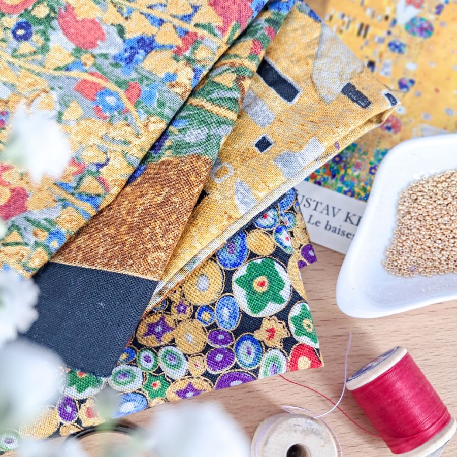 Gros plan sur le tissu d'inspiration Klimt avec motifs dorés et fleurs, base pour l'upcycling de bijoux créateurs français.- pendentifs poupée -Murmures d'une charmeuse