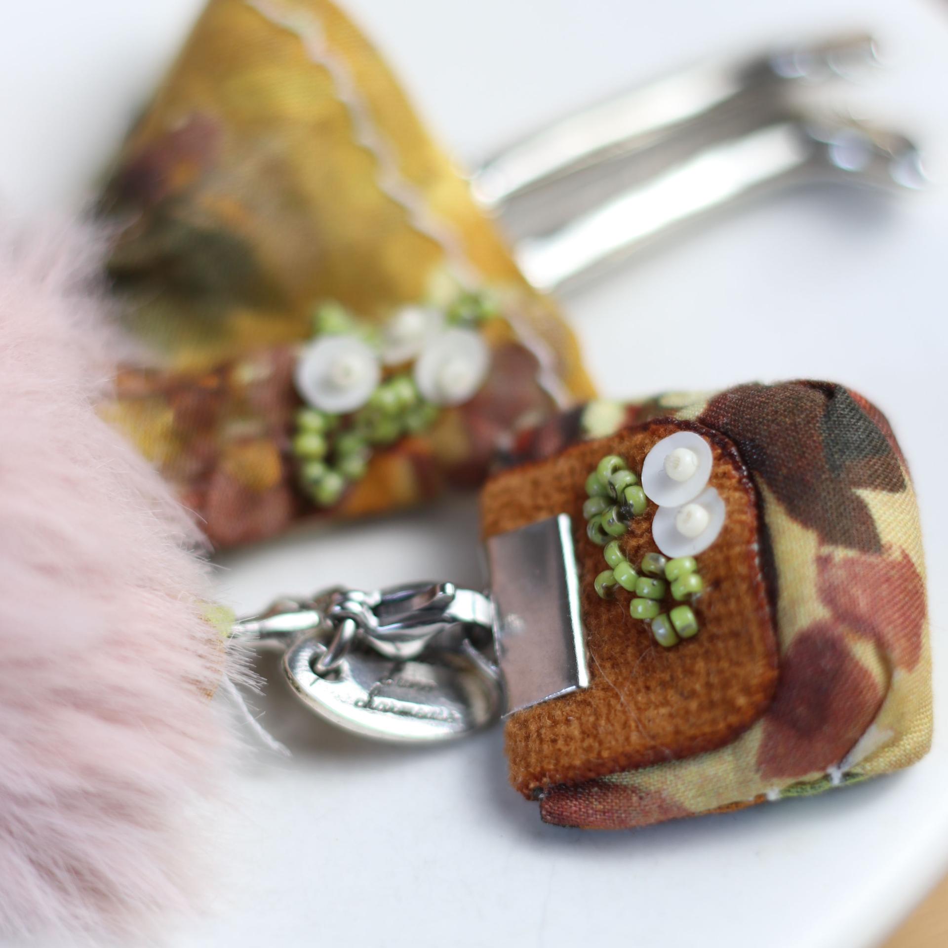 Pendentif poupée articulée Fauve en entier, avec sa chaîne, sur un décor de feuilles d'automne