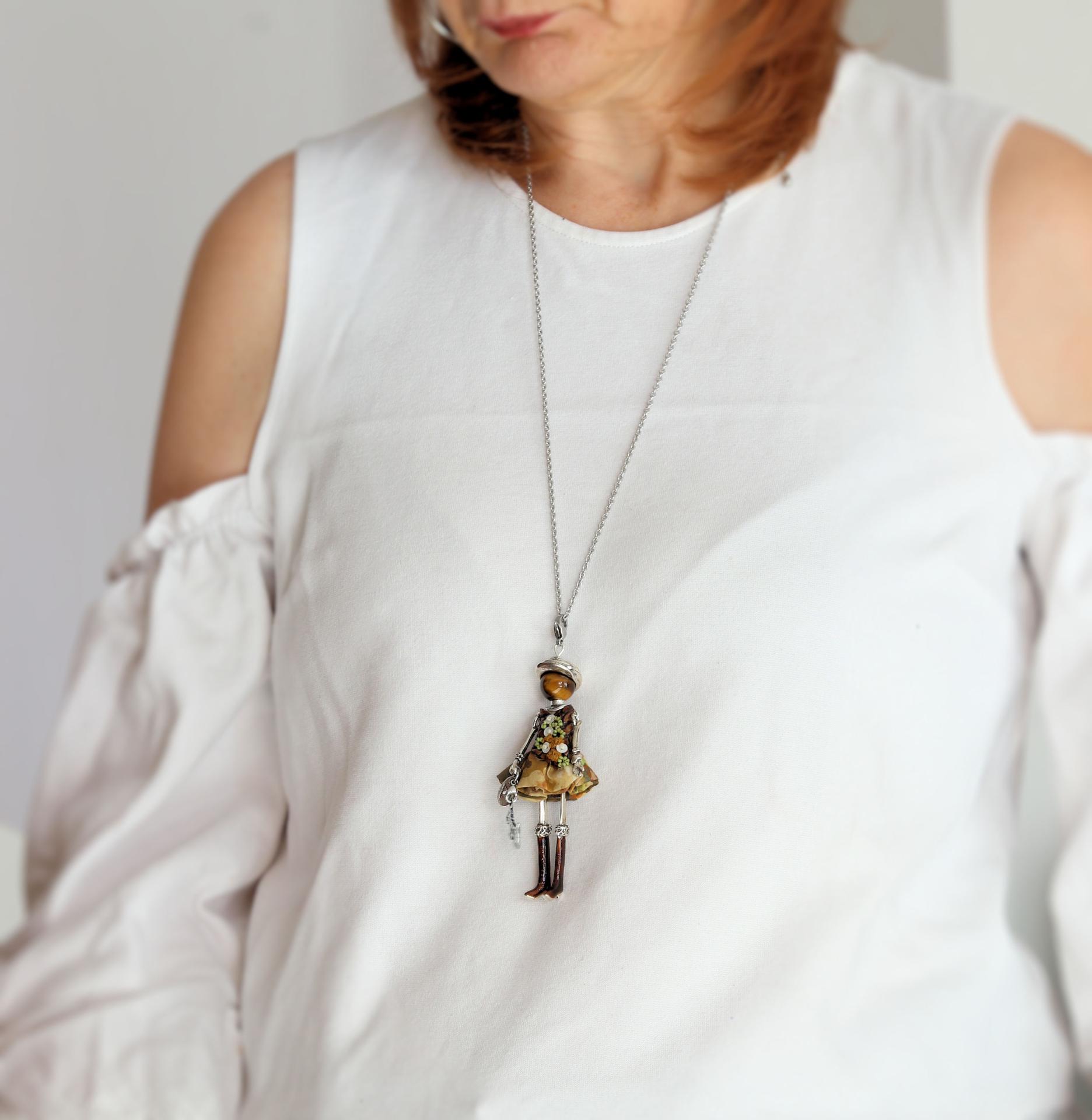 Bijou de protection femme porté : pendentif poupée en œil de tigre sur une tenue d'automne
