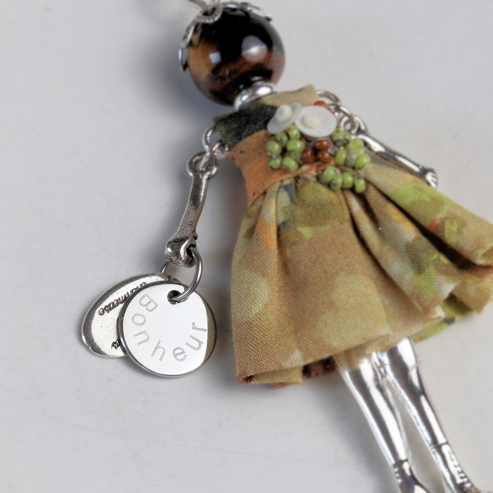 Breloque ronde gravée Bonheur tenue par une poupée pendentif
